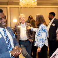 Gentleman leaning on table as he chats with other guest at event